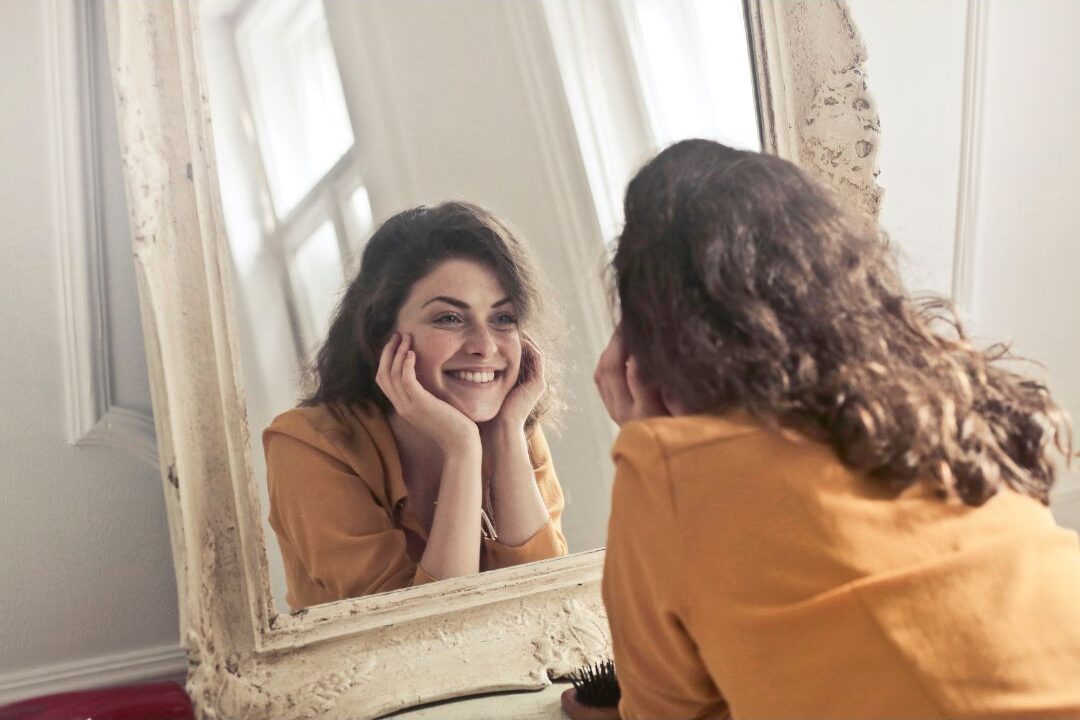 stay at home mom looking in the mirror using affirmations to reconnect with her identity