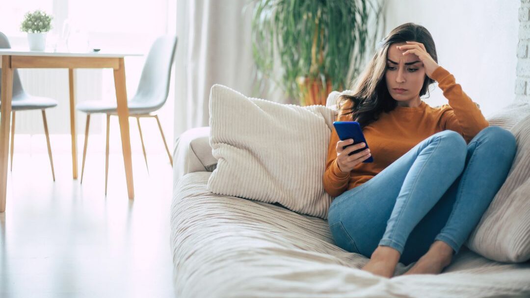 overwhelmed woman looking at her phone handling social invitations