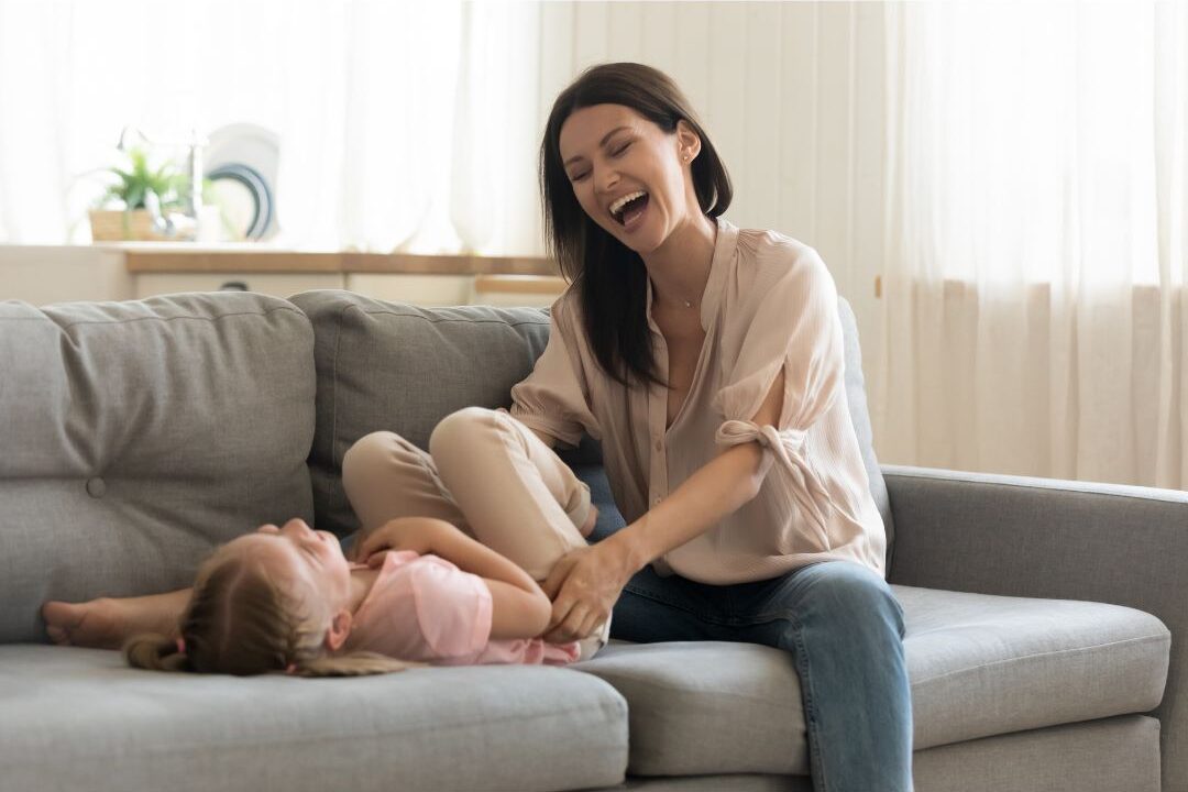 happy mother hugging her child tightly while laughing together at home
