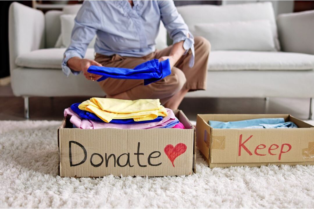 woman happily decluttering her bedroom closet and donating old clothes to clear space