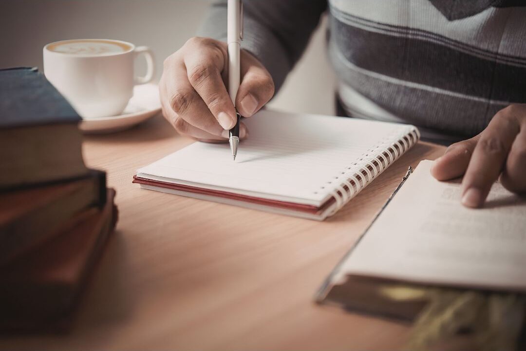 hand writing daily parenting wins in a notebook to stop comparing yourself to other moms