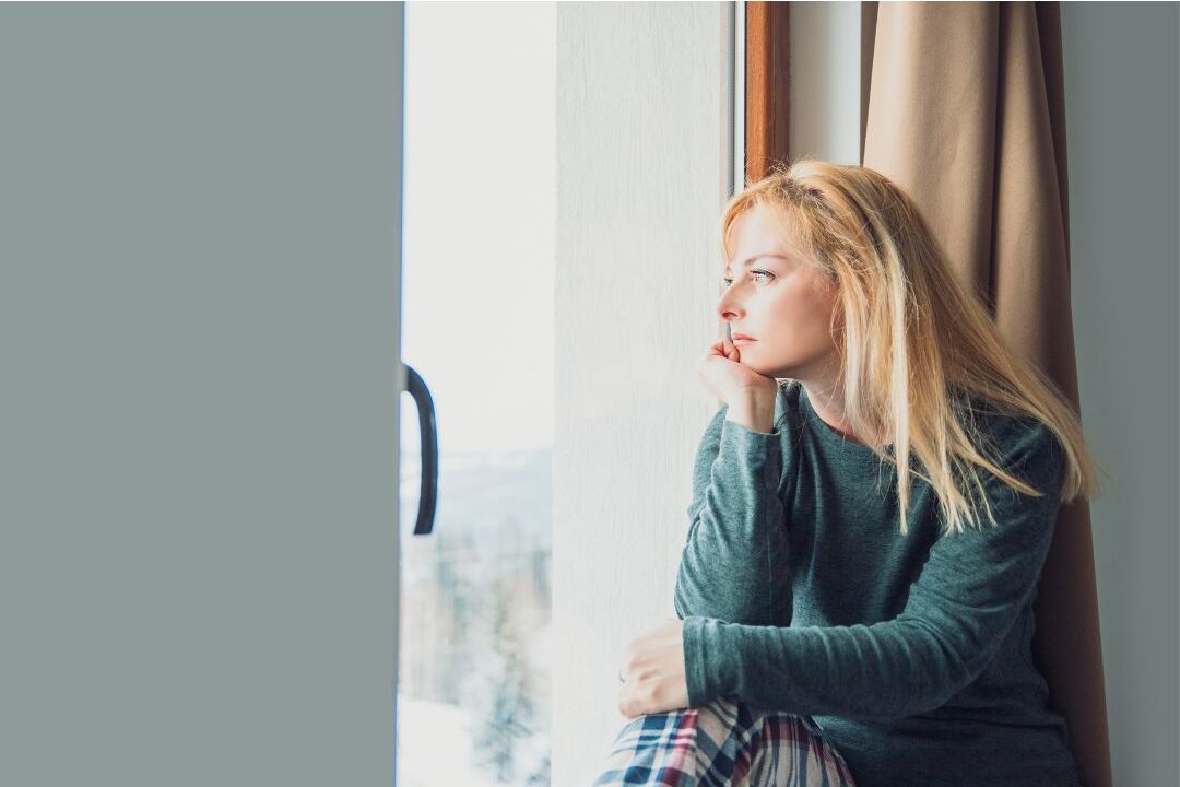 thoughtful distant mother looking out the window experiencing emotional detachment