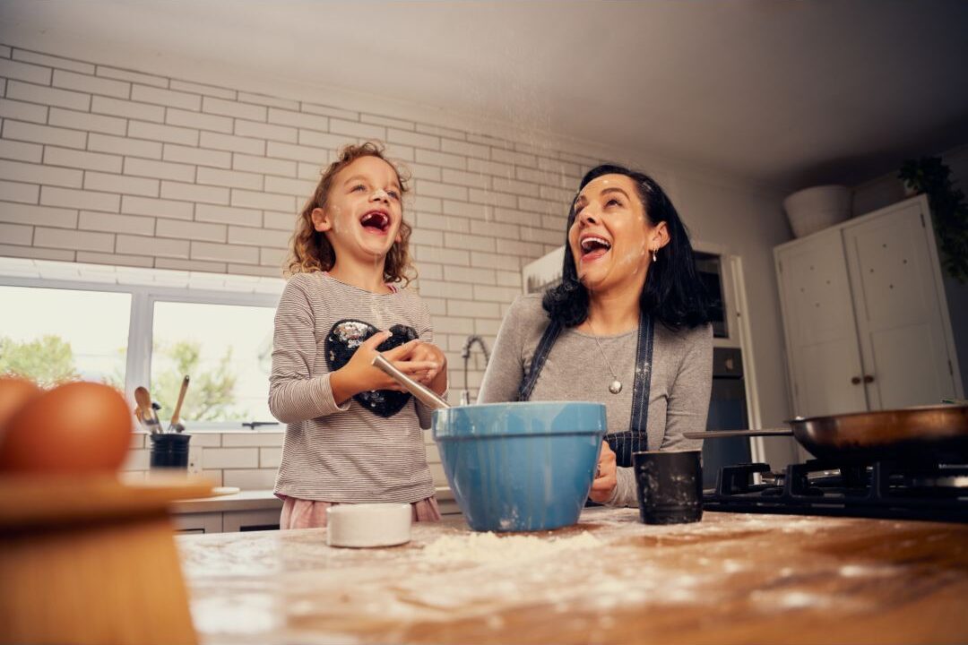 mother laughing in a messy kitchen representing the good enough mother concept