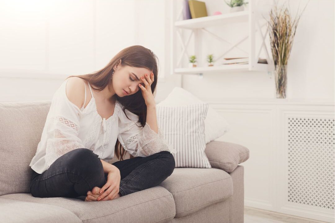anxious woman sitting on a sofa unable to relax due to maternal stress