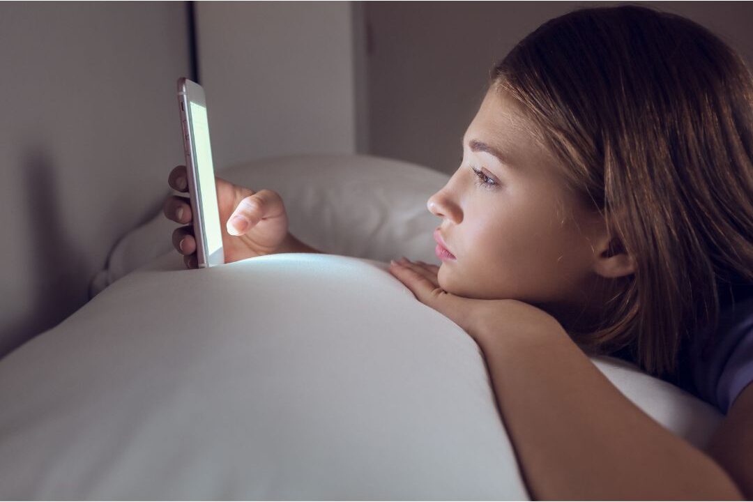woman scrolling her phone looking tired on the couch showing warning signs you're headed for mom burnout