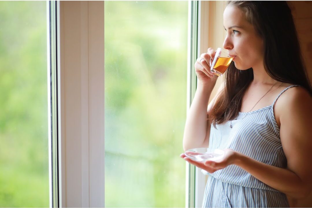 woman drinking tea peacefully by a sunny window taking a micro break