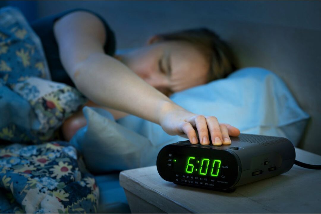 tired mom looking at alarm clock showing the warning signs you're headed for mom burnout