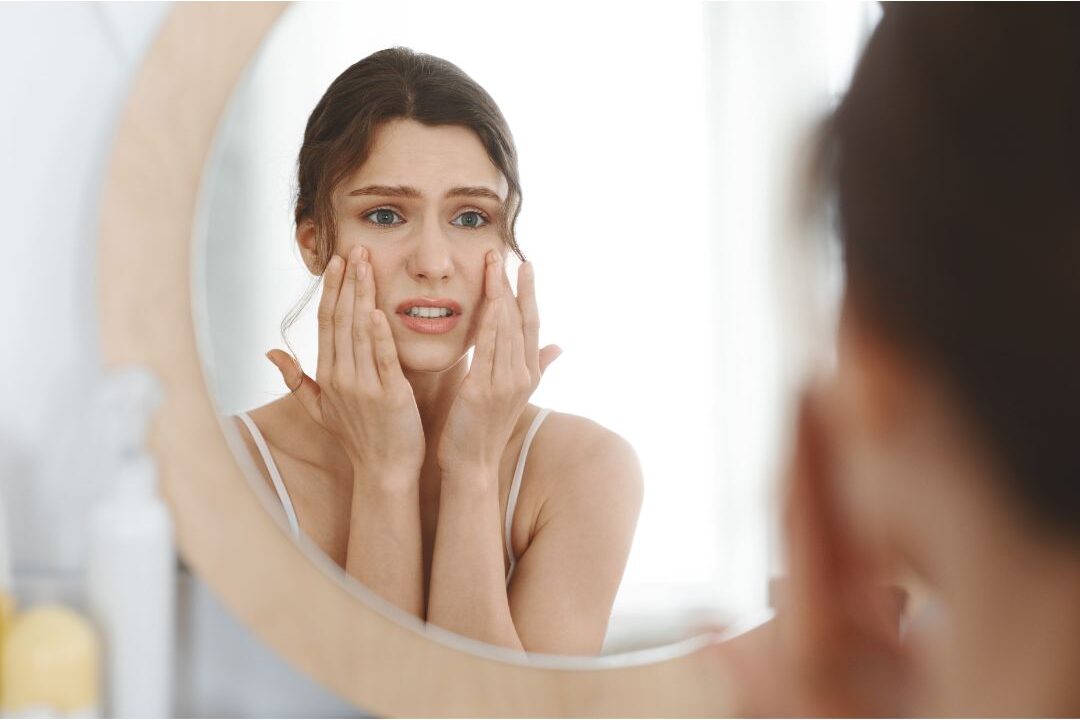 woman looking stressed at skincare products showing why self-care isn't working for you