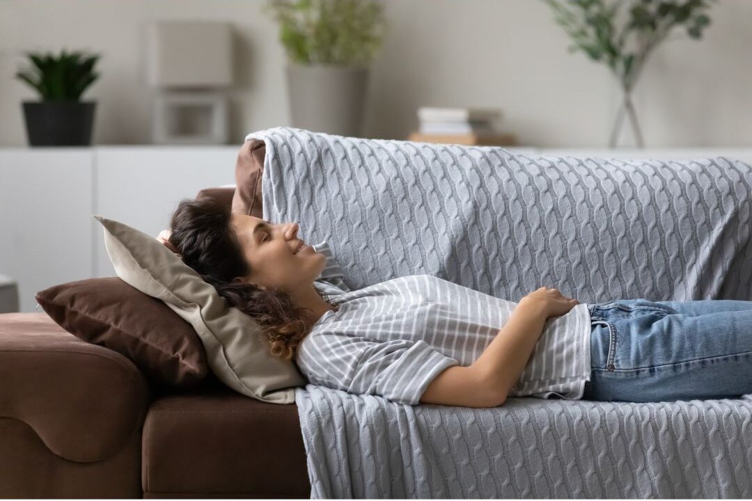a thoughtful mother sitting peacefully on her sofa reflecting on the reality of authentic soft living