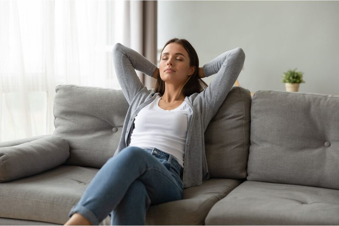 woman resting comfortably on a sofa under warm lighting avoiding self-care mistakes that leave you exhausted