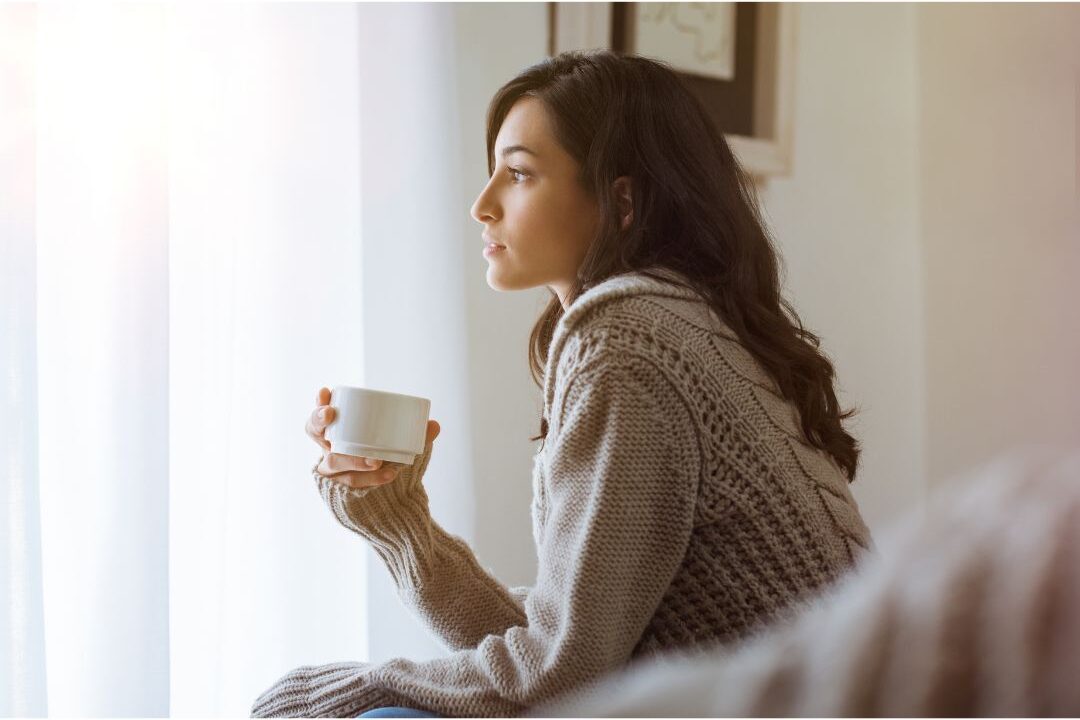 thoughtful mother looking out the window while reflecting on her personal growth