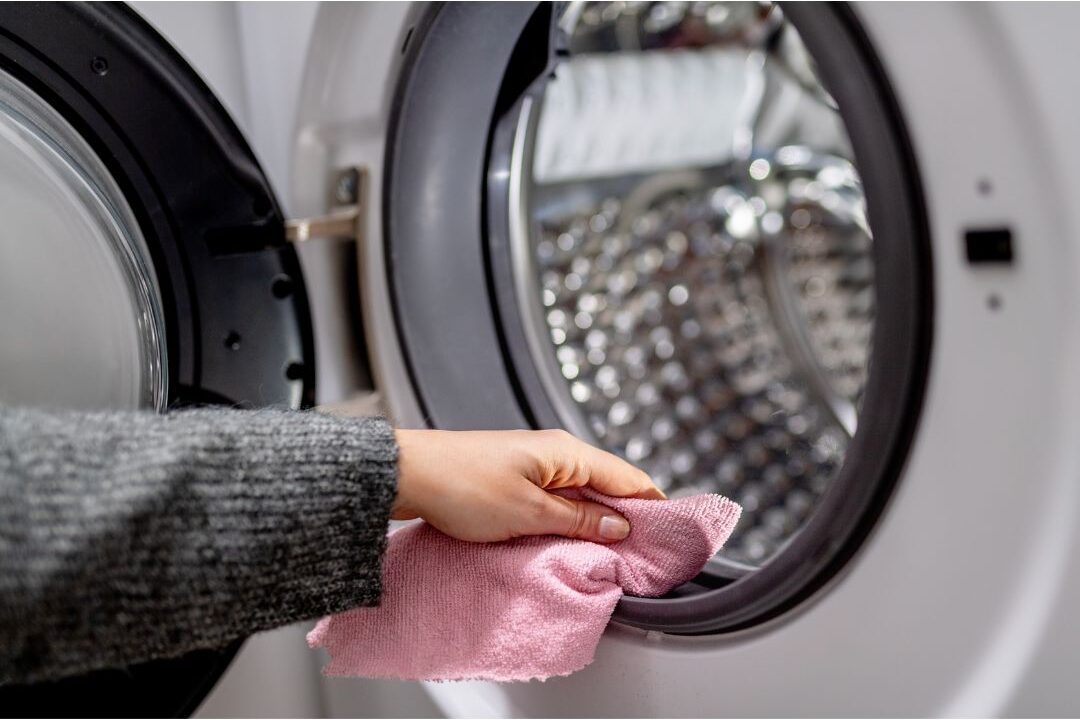 cleaning a washing machine to fix one of the laundry related reasons why a home always smells bad