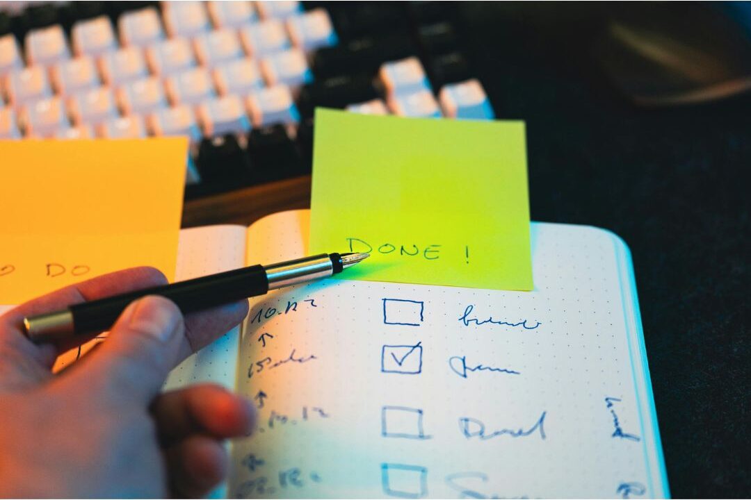 woman planning a checklist in a notebook while sitting at a clean desk space