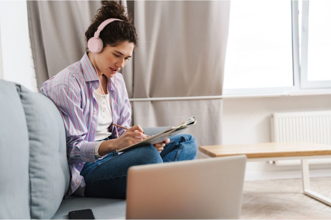 woman writing goals thoughtfully in a journal in a sunny peaceful room