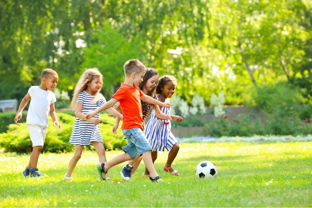 happy children playing soccer in a sunny park field