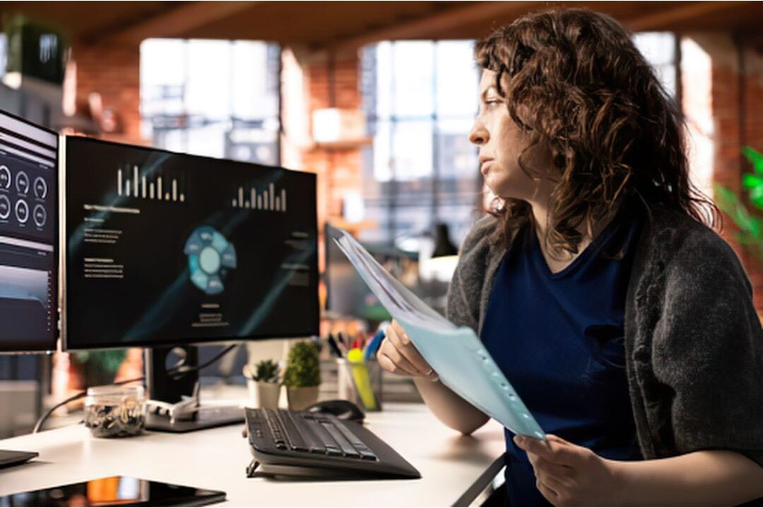 woman reviewing digital notes on a laptop near a sunny window creating ai prompt guides