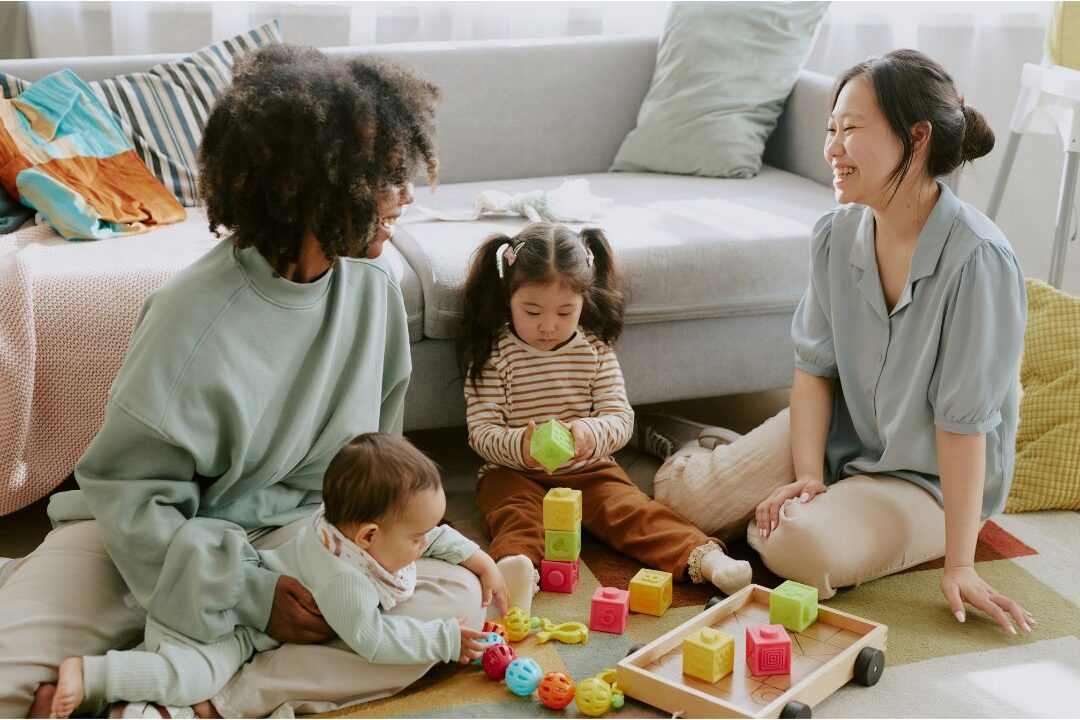 two mothers talking and smiling together while kids play illustrating community support
