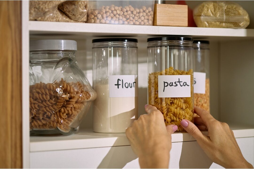 clean organized kitchen pantry with labeled glass jars and wooden bins showing functional systems