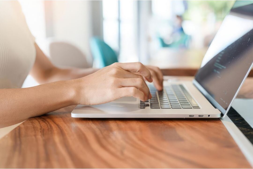 woman typing on a modern laptop keyboard in a bright sunny room