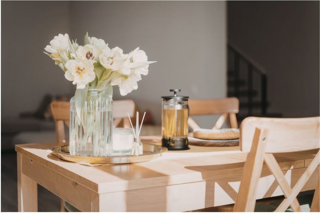 sunlit family dining table with simple vase of garden flowers showing home sanctuary