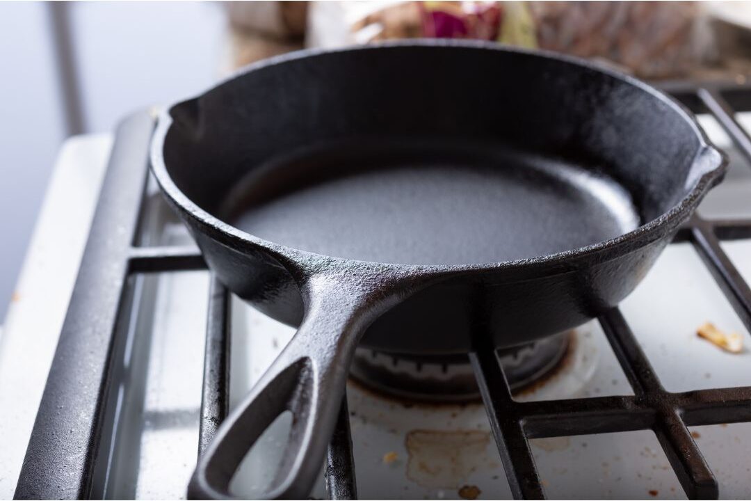 cast iron skillet sitting on a clean stove top as a durable long-lasting cookware choice
