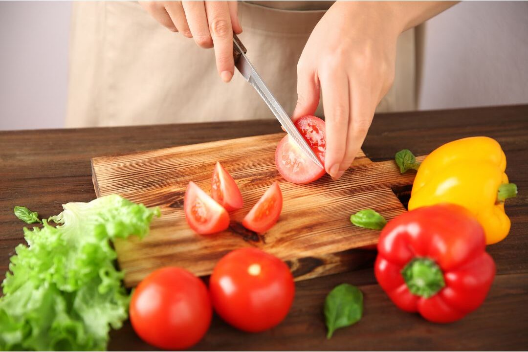 chopping fresh vegetables on a wooden cutting board to avoid pre-cut grocery markups