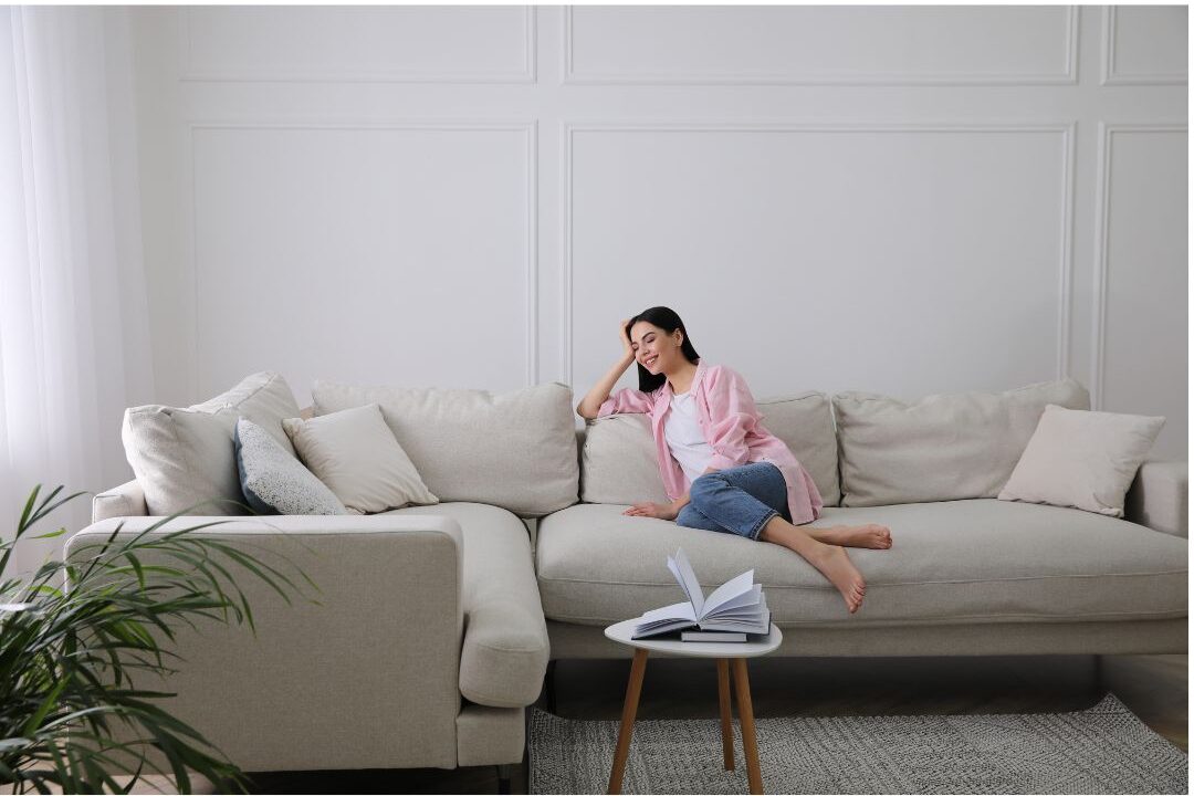 woman resting head peacefully against sofa cushions in sunlit room managing sensory overload