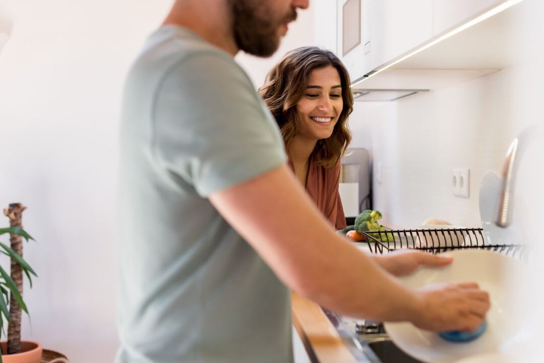 husband helping wash dishes in modern clean kitchen showing shared housework