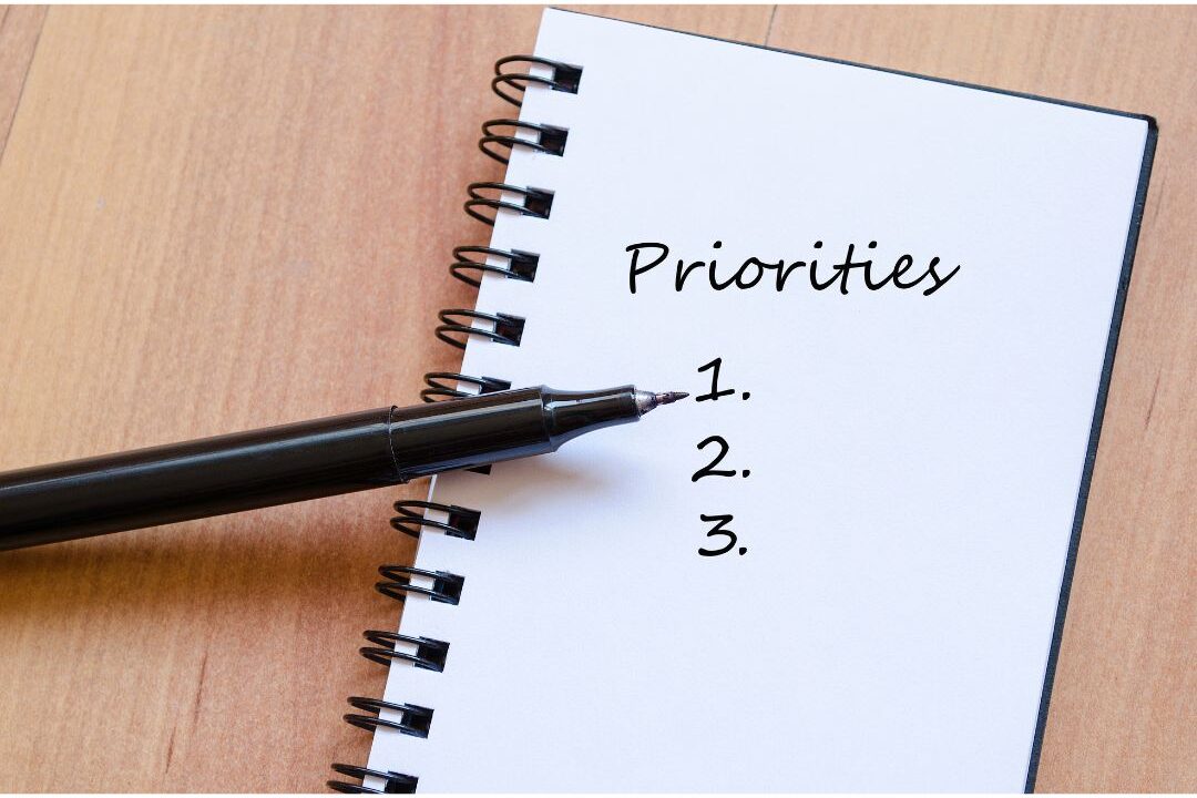 hand writing three simple priorities in daily planner explaining why you never finish your to-do list