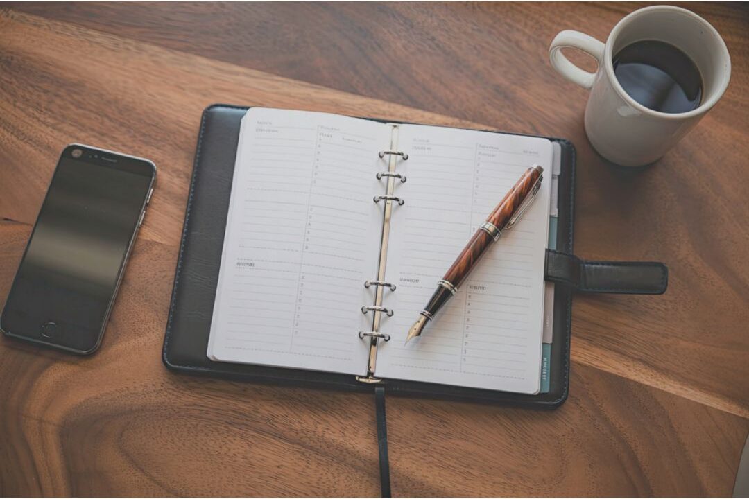 open paper planner on clean wooden table with warm coffee eliminating decision fatigue time-wasting habits