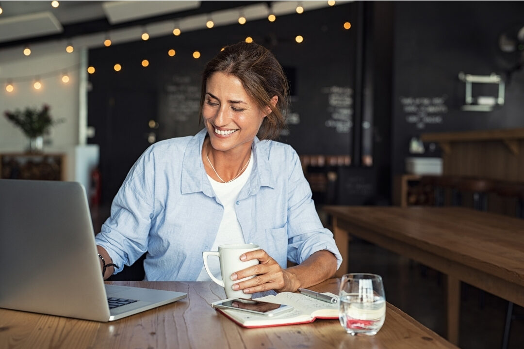 woman smiling looking at completed checklist on laptop screen avoiding 10 mistakes that are killing your productivity at home
