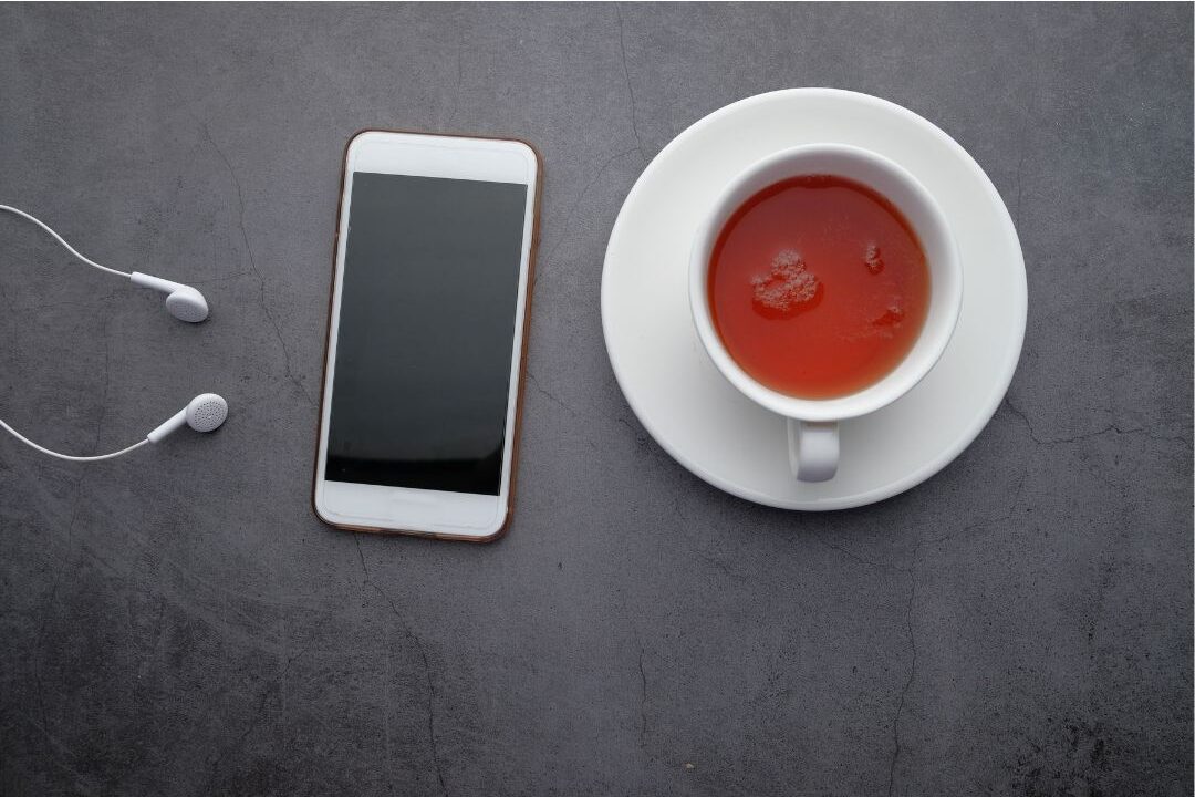 smartphone beside a quiet cup of tea on a wooden desk eliminating digital distraction time-wasting habits
