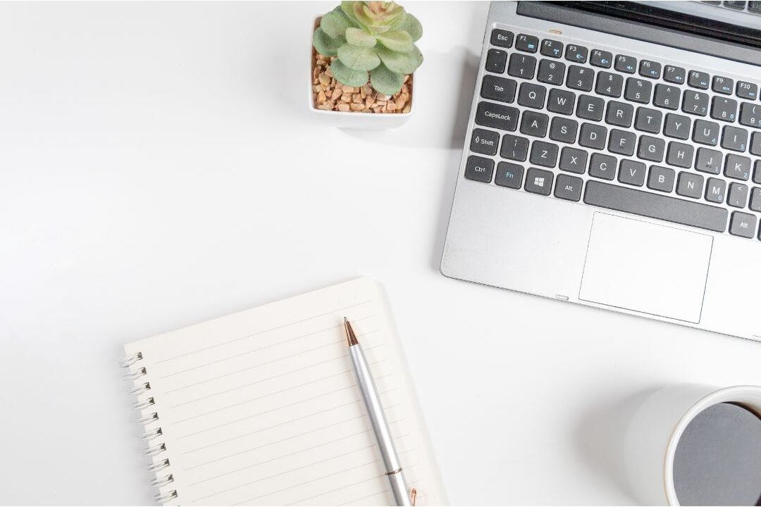 flat lay view of a clean desk workspace with a laptop and notebook detailing passive income streams that actually still work