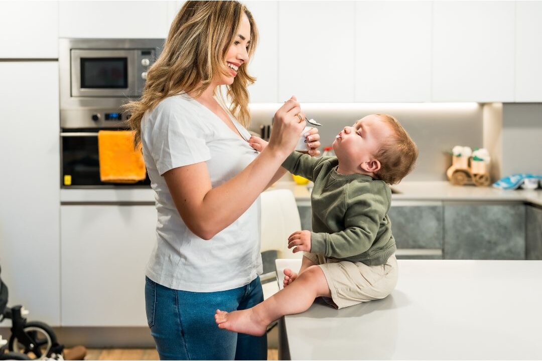 mother laughing with toddler while sitting on kitchen counter showing authentic connection