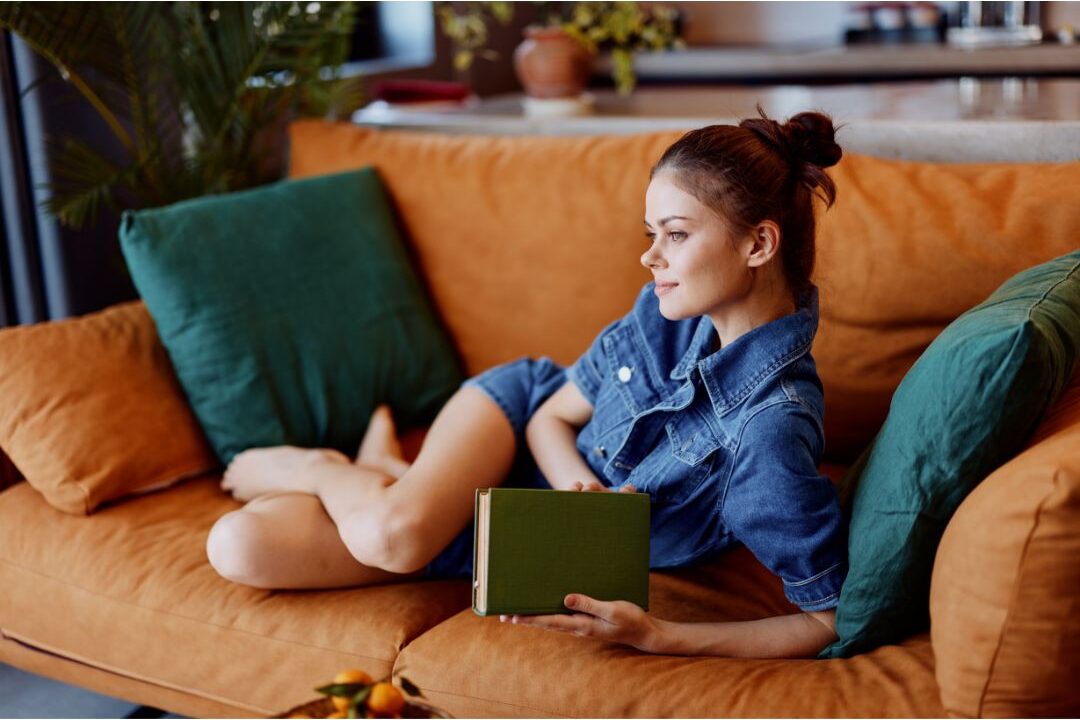 peaceful woman relaxing on couch with book during quiet evening applying the productivity rule every mom should know