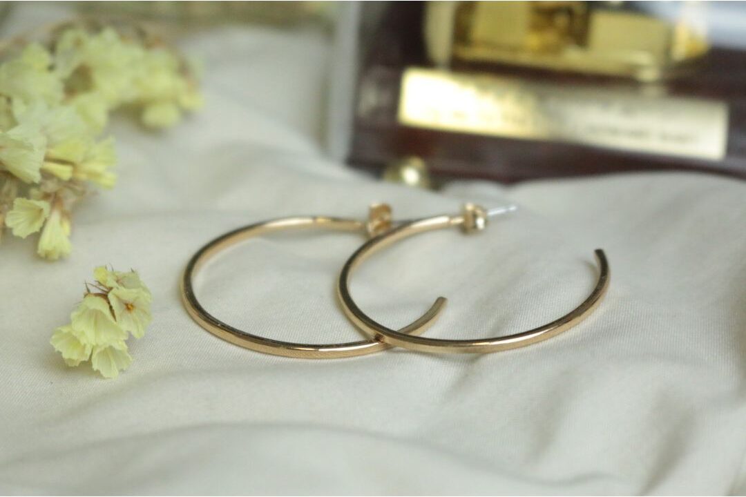 delicate gold hoop earrings and ring resting on ceramic jewelry dish showing fine jewelry