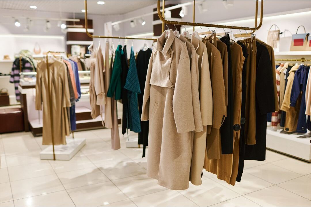 rack of timeless neutral blazers and trench coats in boutique showing classic style