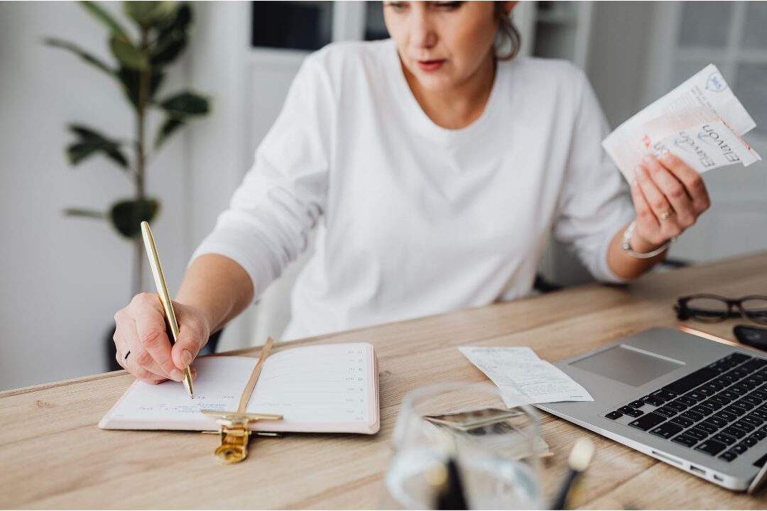 woman writing financial goals in a notebook at a clean desk showing money mistakes stay-at-home moms make solutions