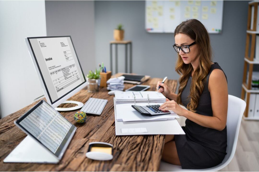 woman reviewing business documents and a calculator on a white desk to avoid the biggest blogging mistakes beginners make