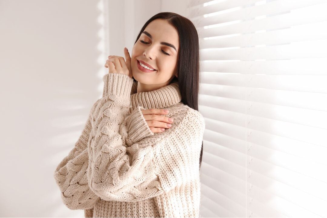 woman wearing thick ribbed cream sweater near window avoiding things stylish women never buy