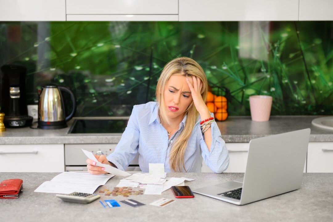 woman looking at a computer screen reviewing monthly bills to catch subscription leaks