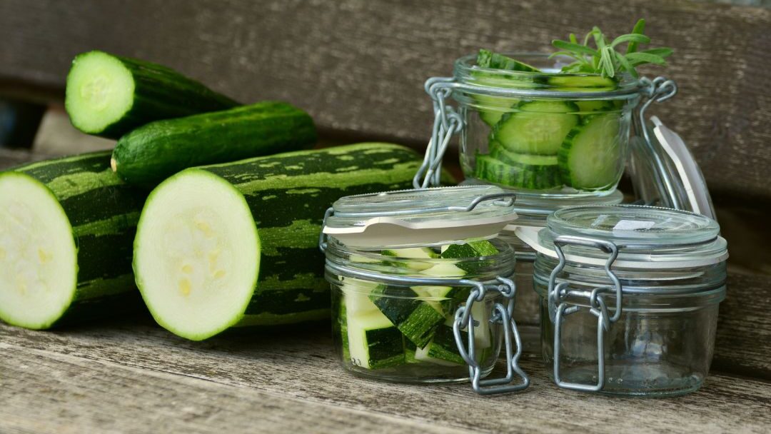 fresh green herbs stored in glass jars of water inside a fridge extending fresh food life