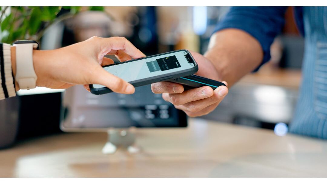 woman holding a smartphone making an easy tap payment at a store counter