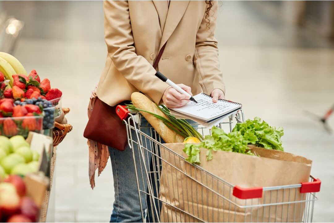 woman pushing a shopping cart through a organized grocery store aisle