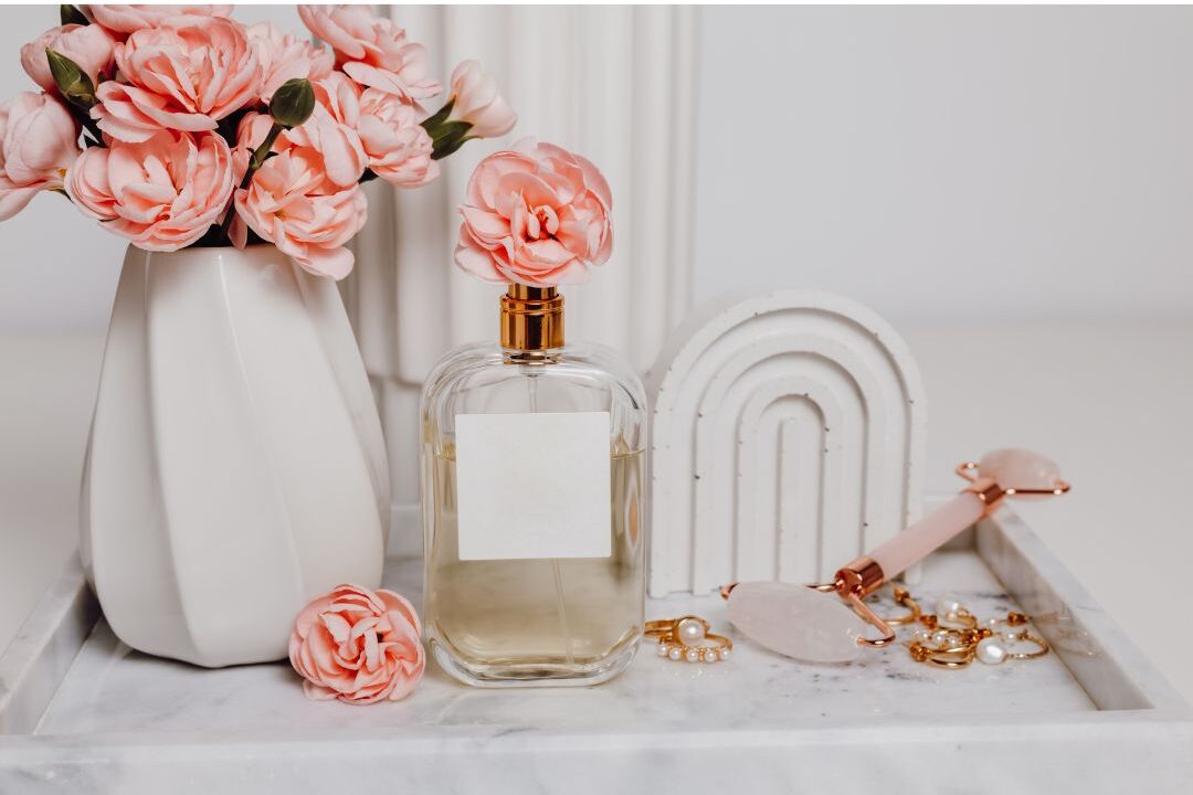 glass perfume bottle resting on marble bathroom tray near fresh flowers showing signature fragrance
