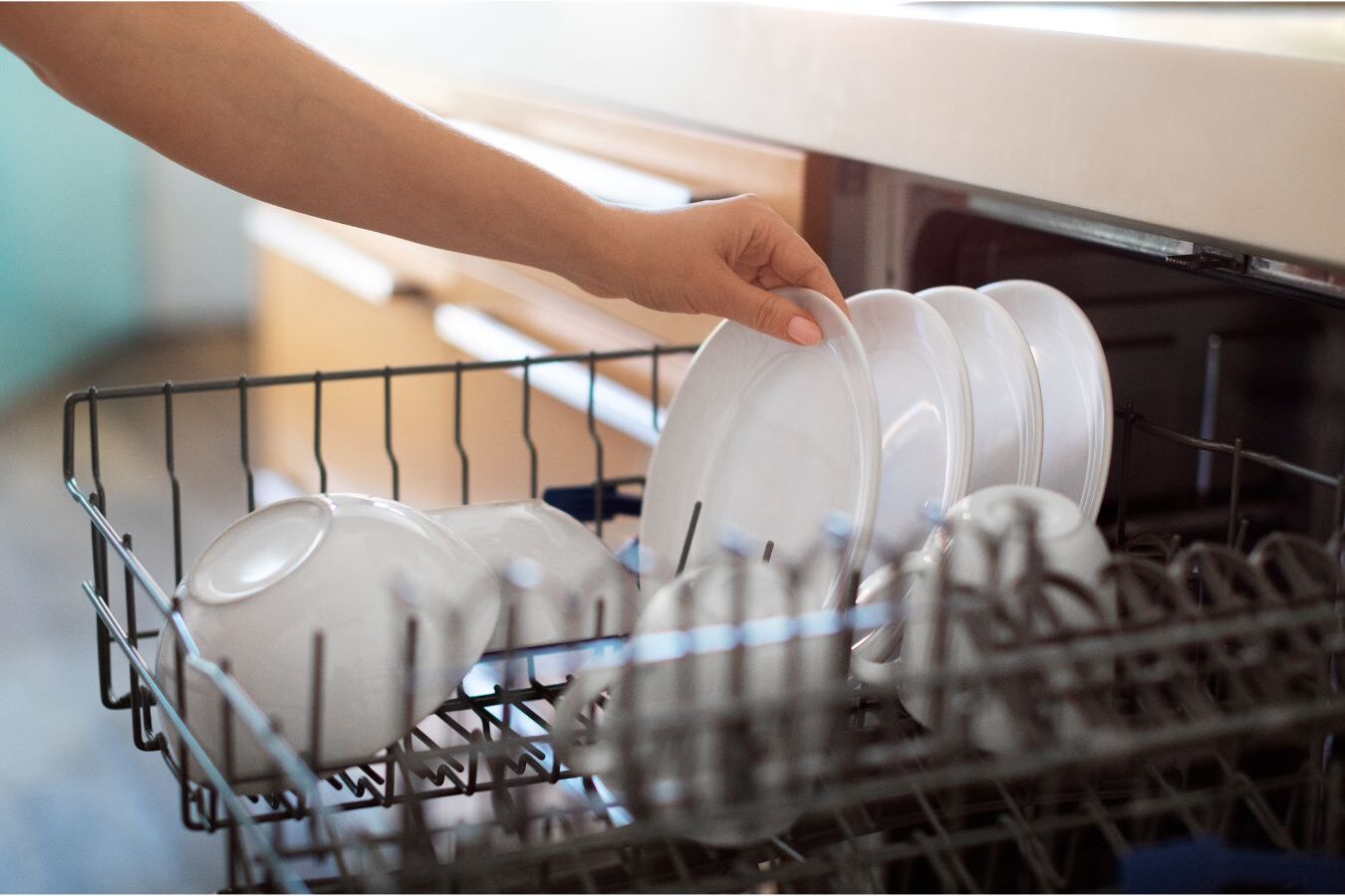 woman calmly unloading clean dishes from dishwasher in sunlit kitchen completing anchor tasks