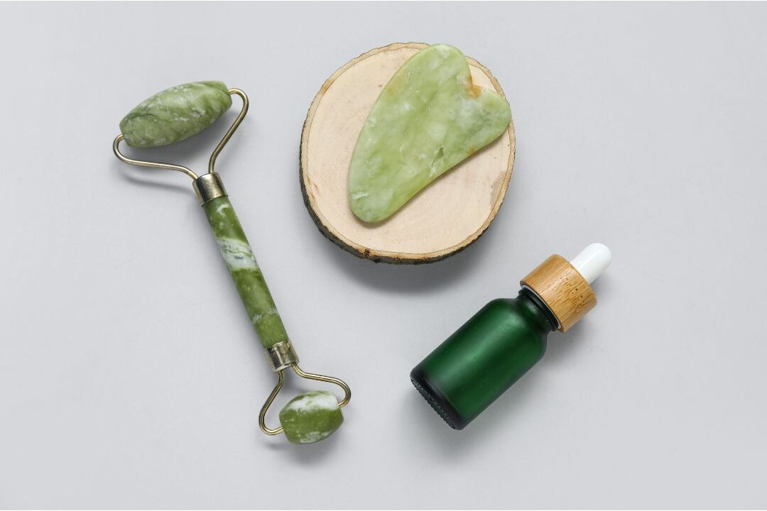 neat skincare bottles and jade gua sha tool on clean vanity tray showing minimal skincare