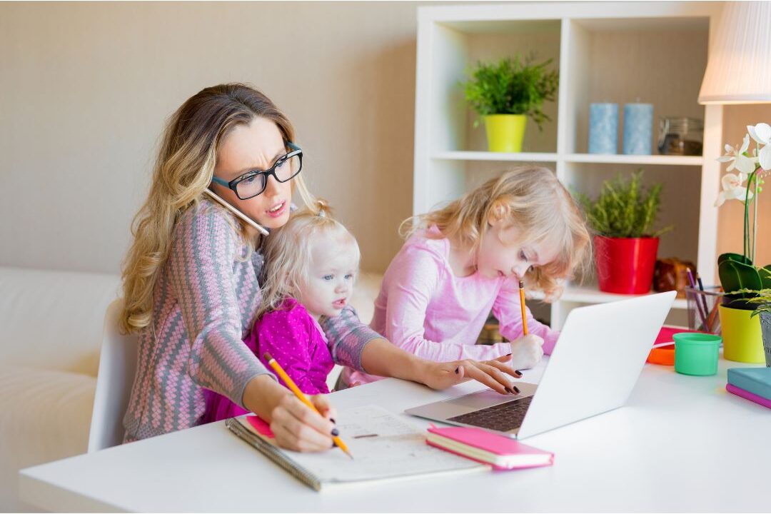 woman working on a computer while managing home environment explaining why most moms never make money online