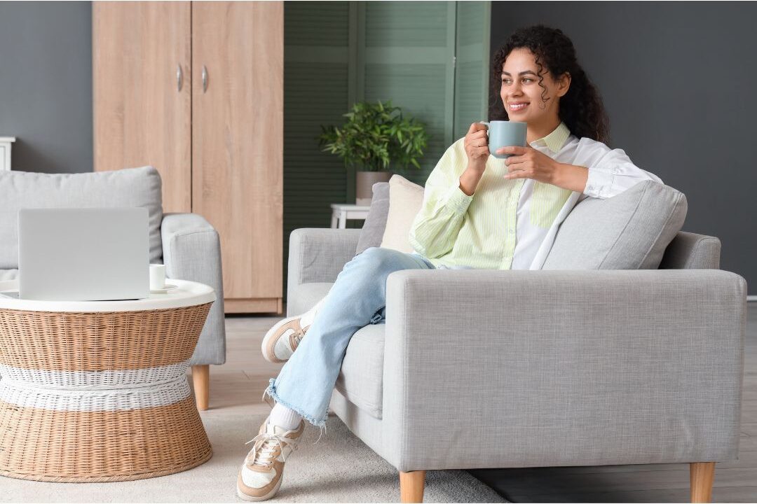 peaceful woman drinking coffee in sunlit cozy living room learning how to love staying home again