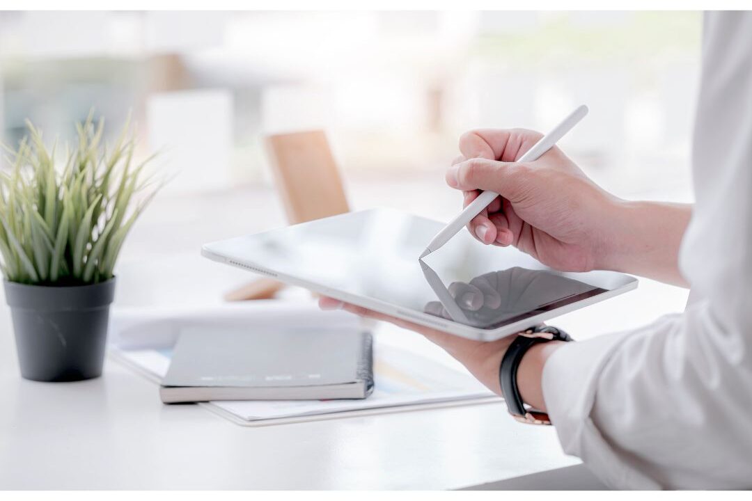 hand holding a digital pen writing on a tablet planner screen illustrating the easiest digital products to sell this year